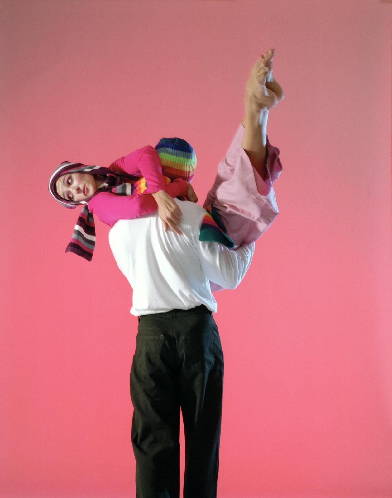 Two figures mid-lift on a pink background