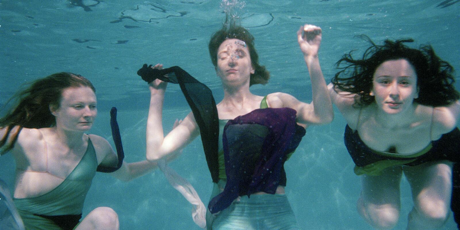 Three figures floating underwater