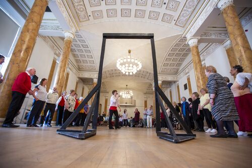 Participants standing in a large circle seen through a freestanding doorframe