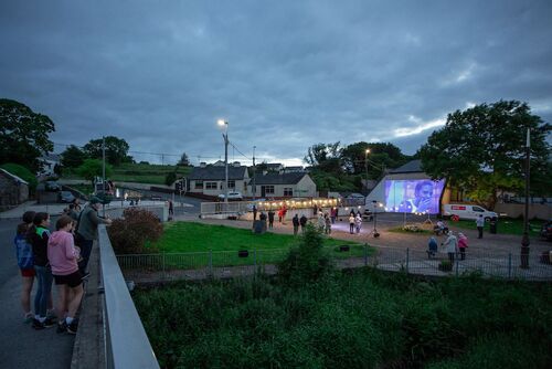 People gathered around a handball alley lit with projections seen from the bridge