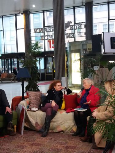 Two people sitting in conversation on a living room couch set-up in Busáras