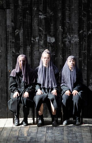 Three figures sitting with sheer veils over their faces