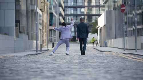 Two figures in suits from behind with one in movement