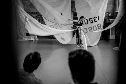 Rosie Stebbing in movement with large ship-sails attached to her waist, rigged to the ceiling