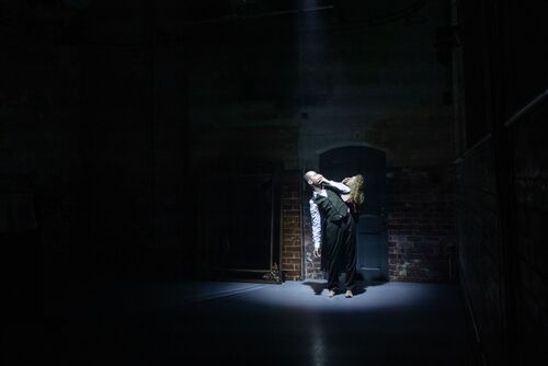 Two dancers spotlit in movement in front of the CoisCéim studio door