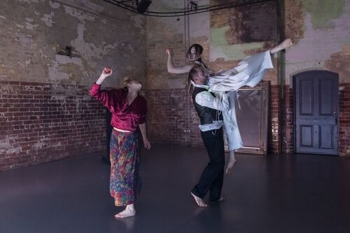Three dancers in movement, two of them mid-lift