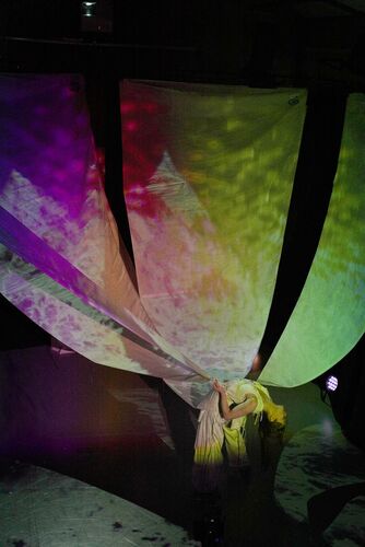 Rosie Stebbing leaning backwards holding large white sails attached to the ceiling