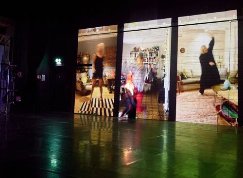 Participants in movement projected on the back wall of a stage