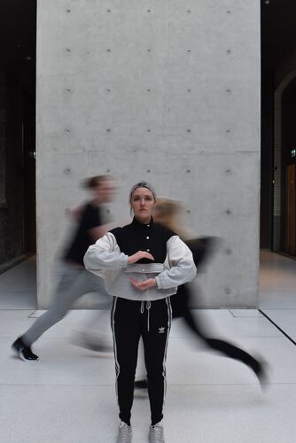 A still figure with two others in blurred motion behind