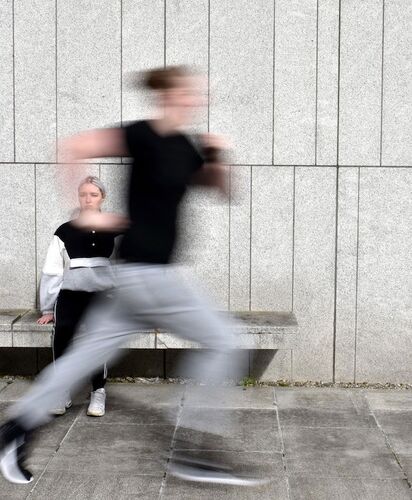 A figure running in a blur past a figure seated