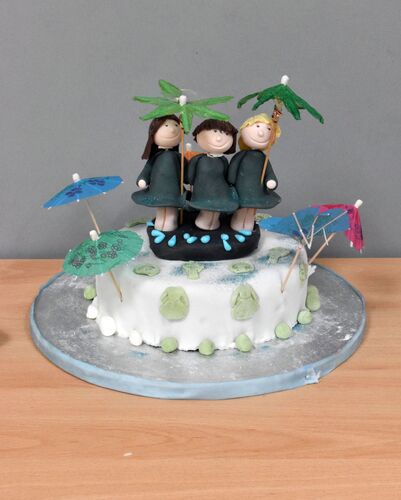 A cake with three figures made of fondant holding umbrellas on top