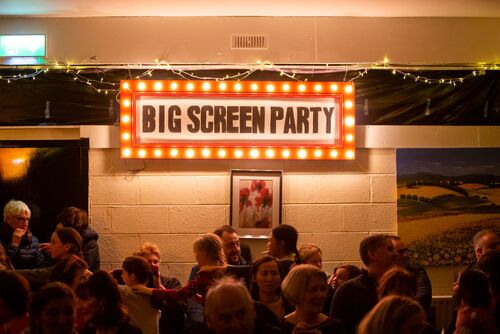 A sign with lightbulbs surrounding it that reads BIG SCREEN PARTY