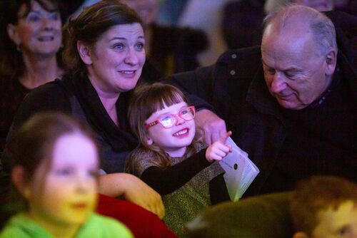 A young child pointing towards the screen and smiling