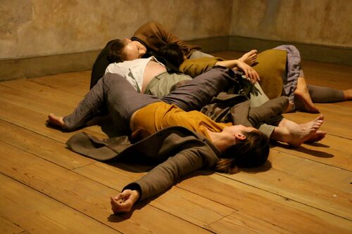 Four figures lying on the floor entwined