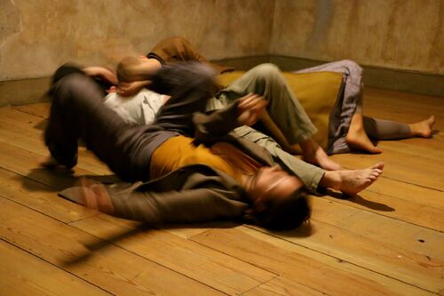 Four figures blurred in motion on the floor with bodies entwined