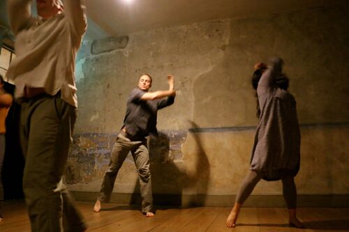 Three figures in movement in the room of a tenement house