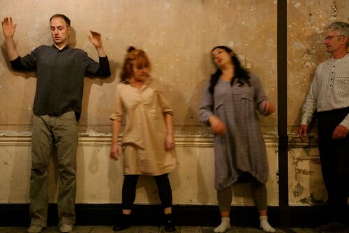 Four figures in movement against a wall