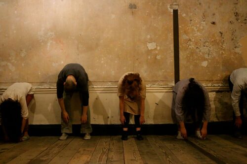 Five figures standing folded over towards the ground