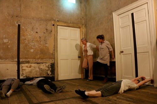 An ensemble of figures in movement in a tenement house room