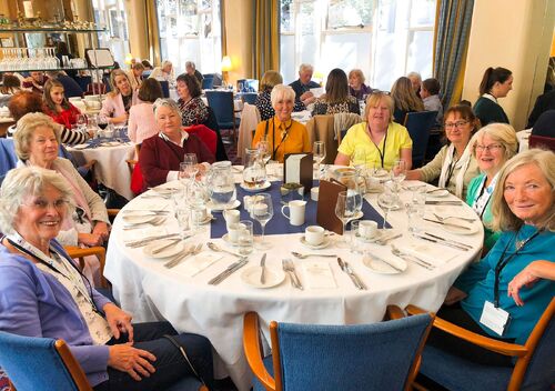Participants seated at a table set for a meal smiling to camera