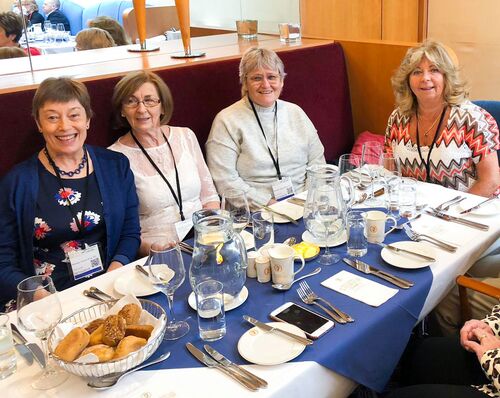 Participants sitting at a table set for a meal smiling to camera
