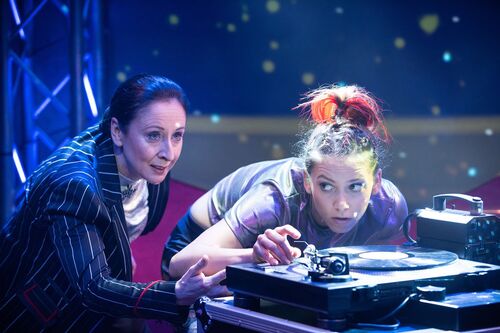 Two figures leaning low over a record player