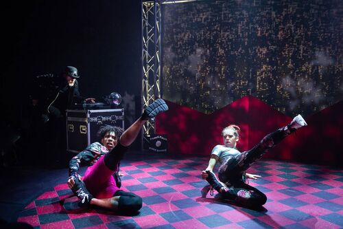 Two dancers in movement on a chequered floor