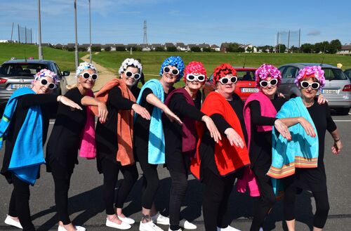 Participants in swimming poses with floral swim caps and dark sunglasses on