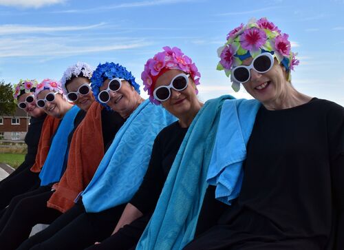 Participants in floral swim caps and sunglasses smiling to camera