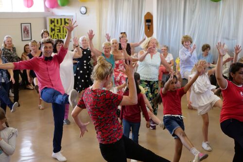 A room of people dancing kicking their legs in the air
