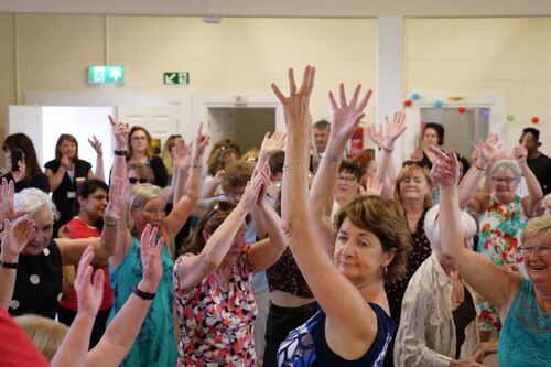 A room of people dancing with their hands thrown in the air