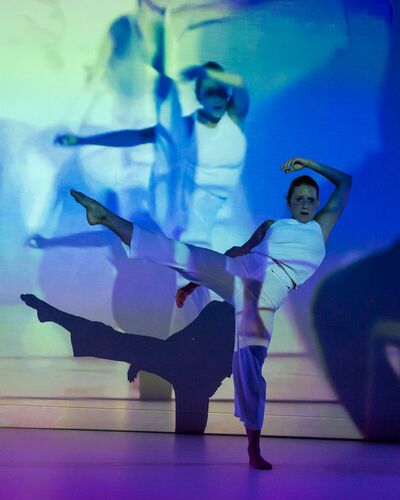 Ivonne Kalter in movement as projections of her movement are cast to the wall behind