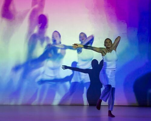 Ivonne Kalter in movement as projections of her movement are cast to the wall behind