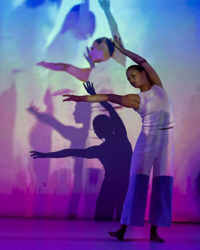 Ivonne Kalter in movement as projections of her movement are cast to the wall behind
