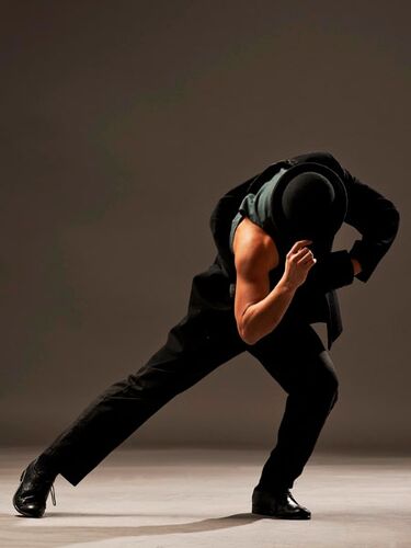A figure in movement dressed all in black with one arm exposed