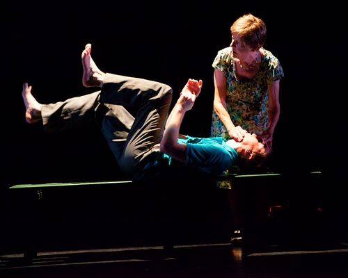 One figure lying on a bench in movement while another holds his chin and forehead