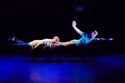 Two figures lying along a bench to simulate swimming through water