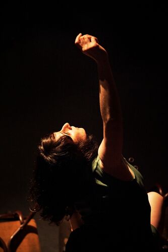 A figure looking up with one arm extended upwards