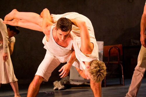 Two dancers in movement with one spread across the others back