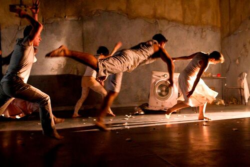 Four dancers in movement towards a source of light