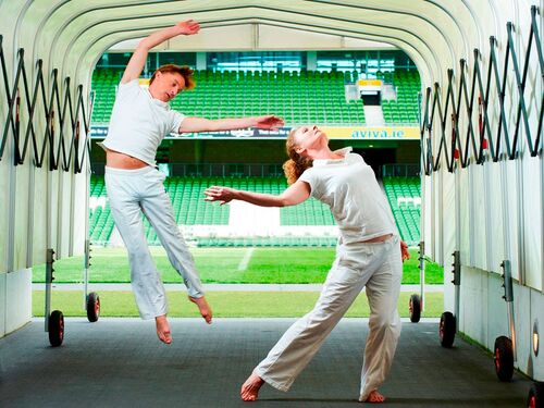 Two figures in movement, one airborne, in the tunnel leading on to a sports pitch