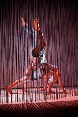 Two figures behind a fringe curtain in movement