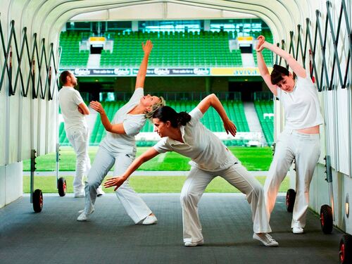 Five figures dressed in white in movement in the tunnel leading on to a sports pitch
