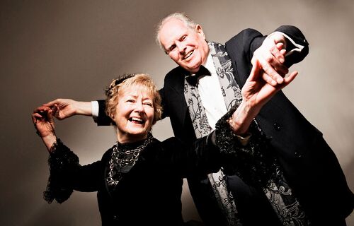 Two participants in black tie dancing together holding hands