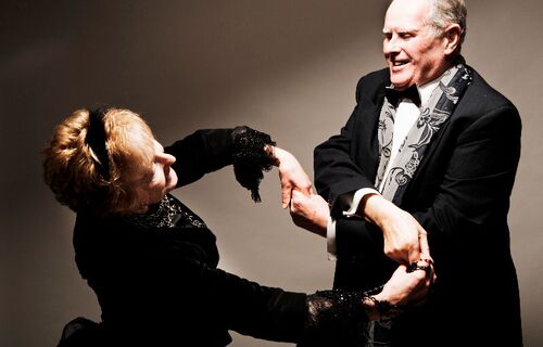 Two participants in black tie dancing together holding hands