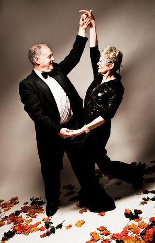Two participants in black tie dancing together holding hands