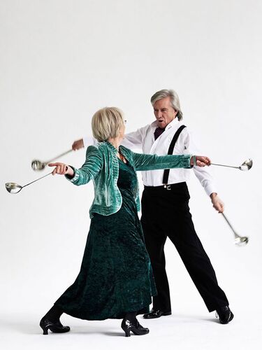 Two figures dancing together holding ladles in each hand