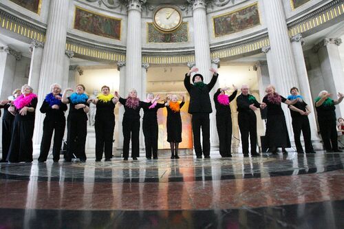 Participants in movement at the centre of City Hall wearing brightly coloured boas