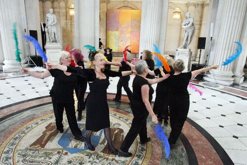 Participants in movement in City Hall holding brightly coloured feathers