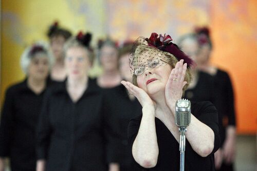 A participant with hands to her face singing at an old fashioned microphone